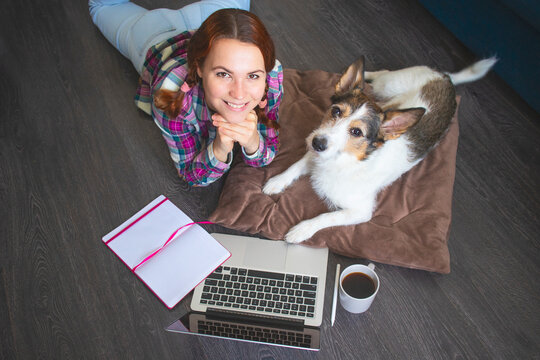Top view, dog and Happy, woman smiling working in laptop, home pet on wooden floor. freelance concept and blogger