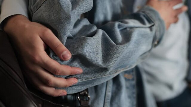 Male caucasian hand squeezes and strokes the elbow of a woman in a denim jacket, she gestures with her hands