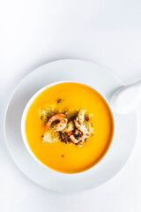 Diet pumpkin soup with shrimp, crouton, turmeric and greens. Healthy food. White background.