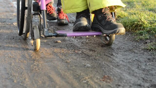 Disabled person in a wheelchair on a muddy path and a care taker