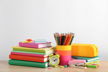 Fototapeta premium Different school stationery and alarm clock on table against white background, space for text. Back to school