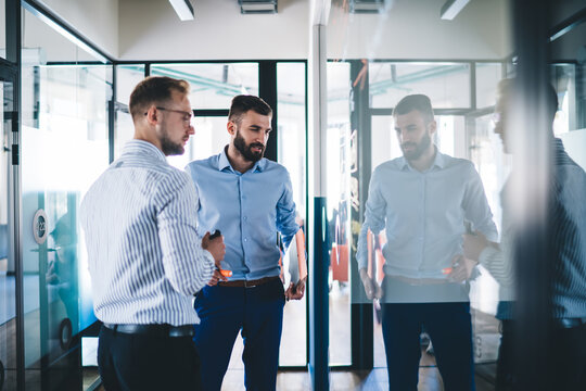 Young 20s male professionals discussing solutions on meeting enjoying productive cooperation, skilled men experts looking at infographic and sketches checking analytic together for startup