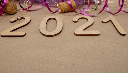 Light wooden numbers 2021 lie in the center on craft paper with packing tape, champagne corks, gold bow