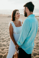 .Young pregnant couple taking pictures on the beach at sunset. Loving couple. Pregnancy