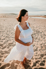 Fototapeta na wymiar .Single and pregnant woman taking pictures on the beach at sunset. Excited and relaxed. Lifestyle