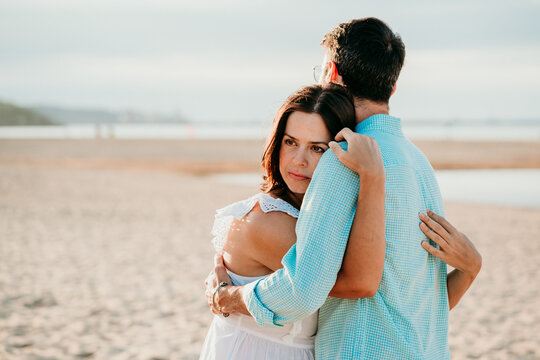 .Young pregnant couple taking pictures on the beach at sunset hugging each other feeling happy. Lifestyle