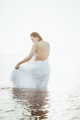 Fototapeta na wymiar Female in wedding dress in water. Naked torso. Partly dressed. High quality photo