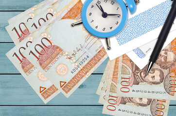 100 Dominican peso bills and alarm clock with pen and envelopes. Tax season concept, payment deadline for credit or loan. Financial operations using postal service