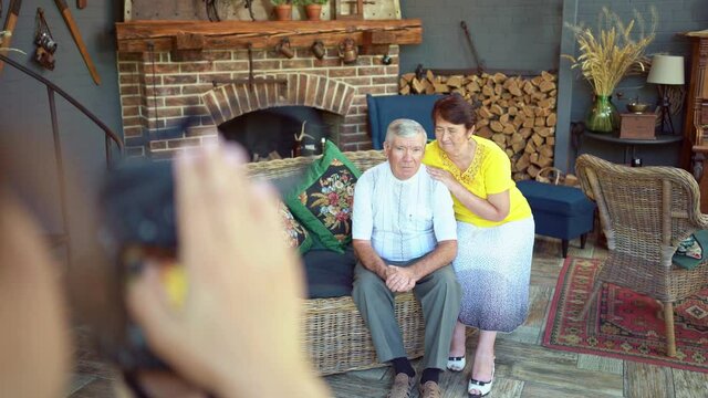 elderly couple in chair in country house by fireplace. backstage photo shoot.