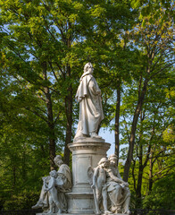 Fototapeta premium Marble angel statue in a cemetery with green trees