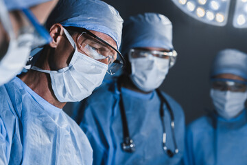 Concentrated surgeons operating patient in operating theatre. Healthcare workers concept. - obrazy, fototapety, plakaty