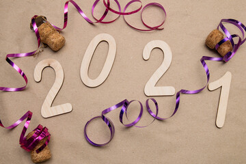 Light wooden 2021 numbers lie randomly on craft paper with champagne corks, packing tape and muzlet