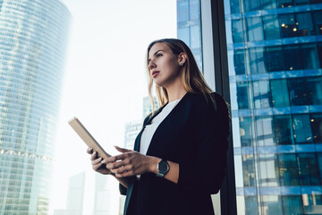 Concentrated female entrepreneur using tablet near window