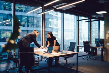 Confident male and female architects talking to each other brainstorming and cooperate on project in office interior, intelligent business partners preparing finance report communicating and analyzing