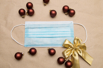 Naklejka na ściany i meble Medical face mask lies on craft paper with golden bow and christmas balls toys