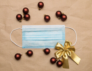 Naklejka na ściany i meble Medical face mask lies on craft paper with golden bow and christmas balls toys