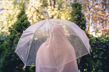 Autumn. Lonely muslim woman in a headscarf under a transparent umbrella with rain drops walking in a park, garden. Rainy day landscape. Vintage Toned