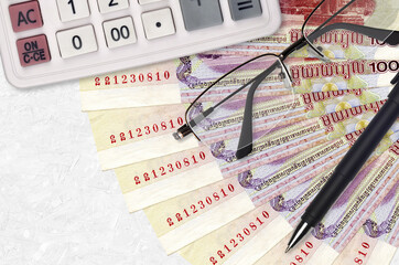 100 Cambodian riels bills fan and calculator with glasses and pen. Business loan or tax payment...