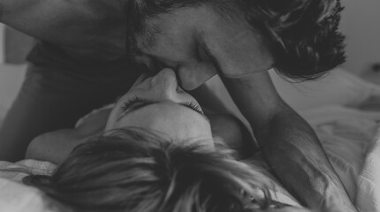 Romantic couple in love kissing on the bed at home. Boyfriend and girlfriend having romantic moment together. Black and white filter.