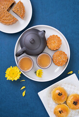 Moon cake for Mid-Autumn Festival, delicious beautiful fresh mooncake on a plate over blue background table, top view, flat lay layout design concept.