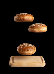baked round bun with sesame seeds hover over brown wooden cutting board