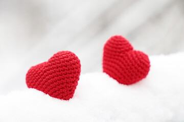 Fototapeta premium Valentines hearts, greeting card, two red knitted symbols of love in the snow. Background for Christmas holiday, celebration or winter weather