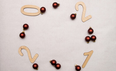 Light wooden numbers 2021 are scattered on a white background around the edges with Christmas balls