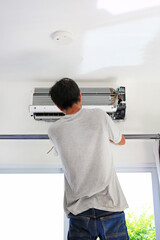 Technician preparing to installs new air conditioner on white wall in the room.