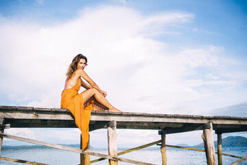 Young woman in yellow dress sitting on pier