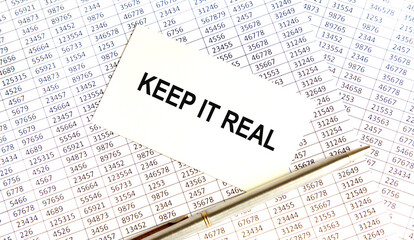 Obraz premium KEEP IT REAL text on paper sheet with chart, dice, spectacles, pen, laptop and blue and yellow push pin on wooden table - business, banking, finance and investment concept