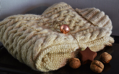 Zopfpullover aus schafwolle als Weihnachtsgeschenk mit Christbaumkugel, Farben Pink, Grün, Weiß, grauer Hintergrund