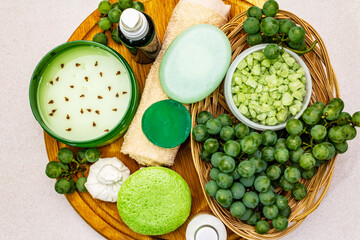Natural spa accessories and green grapes placed on a wooden plate