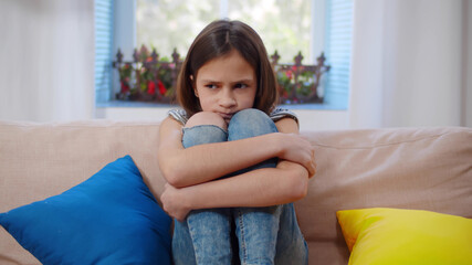 Depressed Schoolgirl Suffering From Loneliness Sitting On Couch At Home