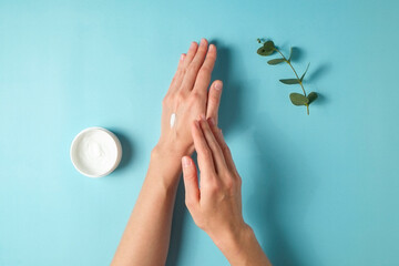 Revitalizing hand cream for healing and recovery after excessive use of soap and disinfectants. Young woman applying moisturizing lotion. Copy space, close up, pink background, flat lay, top view.