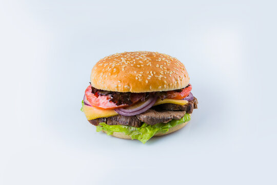 Beef burger with vegetables and cheese in wheat bun with sesame seeds. Meat veal Burger with fresh salad leaves, tomatoes, Spanish onions isolated on white background. Food Isolation 
