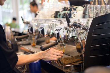 Barista making a cup of coffee by coffee machine in cafe
