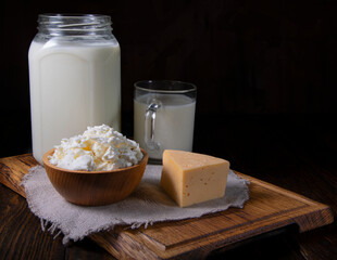 The photo shows milk in a container and a cup, cheese, and cottage cheese.