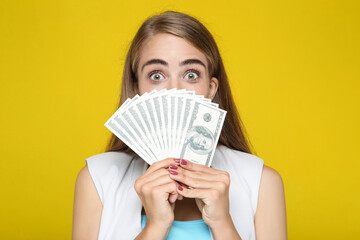 Beautiful woman holding dollar banknotes on yellow background