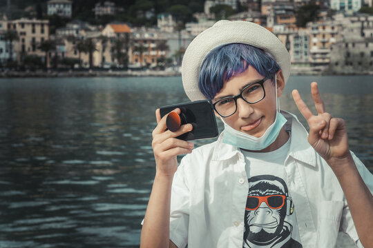 young boy with colored hair and mask taking a selfie at the port of rapallo during a summer vacation
