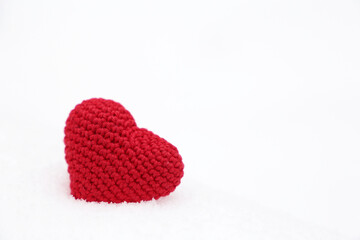 Red knitted heart in the snow. Background for Christmas card or Valentine's day
