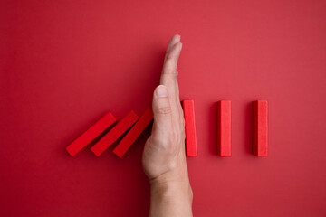 red domino blocks that begins to fall and a hand that prevents it from falling.