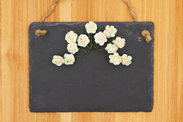 Fototapeta na wymiar Spring blank hanging chalkboard sign with white roses sign on wood