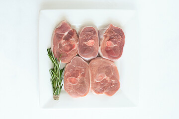 pieces of raw turkey meat, chopped leg steak, portioned barbecue pieces, on white background with a sprig of rosemary and red hot pepper. isolate