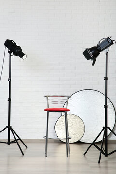 Professional studio equipment with chair on white brick wall background