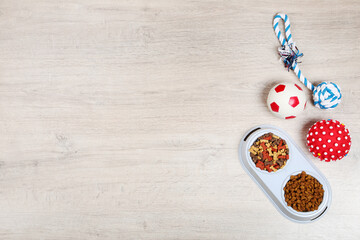 Dry pet food in bowls with toys on the floor