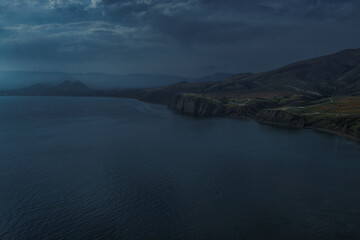 view of beautiful dark coast with road of bay of sea with water among hills and high mountains. Crimea, Russia, evening cloudy landscape