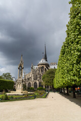 Notre Dame cathedral seen from the garden with green trees and cloudy sky