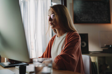 Young beautiful woman in spectacles working at modern home interior on computer, Female graphic...