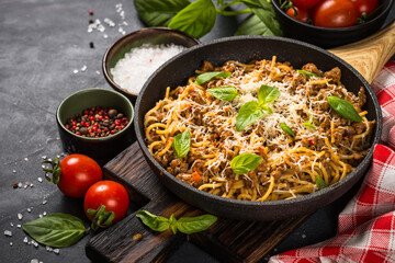 Pasta Bolognese in the skillet at black table.