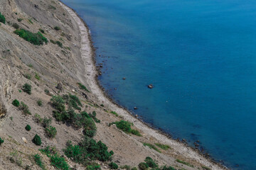 view of beautiful stones coast with green trees of bay of sea with blue water. Crimea, Russia, summer sunny landscape